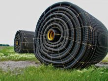 Two large rolls of tile drainage tubing sit in a field ready to be installed.