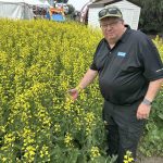 Western Producer Markets Desk analyst Bruce Burnett inspects a canola plot at Ag In Motion 2025. PHOTO: SEAN PRATT