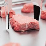 A robotic arm arranges slabs of artificial meat.