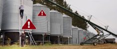 Farmers loading grain into a row of grain bins with safety warnings in risky areas.
Photo: AJ_Watt/istock/getty images