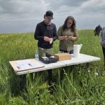 Neal Wagar with EcoTea and Mary-Jane Orr, general manager of Manitoba Beef and Forage Initiatives, test soil treated with EcoTea during a field day at the organization's Brookdale farm on Aug. 12, 2025.