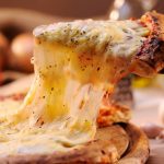 Cheese stretches off of a pizza slice. Photo: Moncherie/iStock/Getty Images
