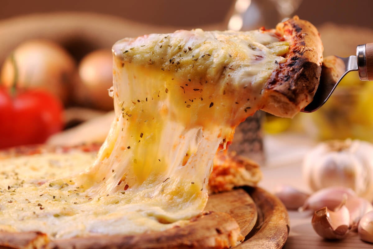 Cheese stretches off of a pizza slice. Photo: Moncherie/iStock/Getty Images