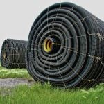 Rolls of tile drainage piping sit a field, waiting for installation.