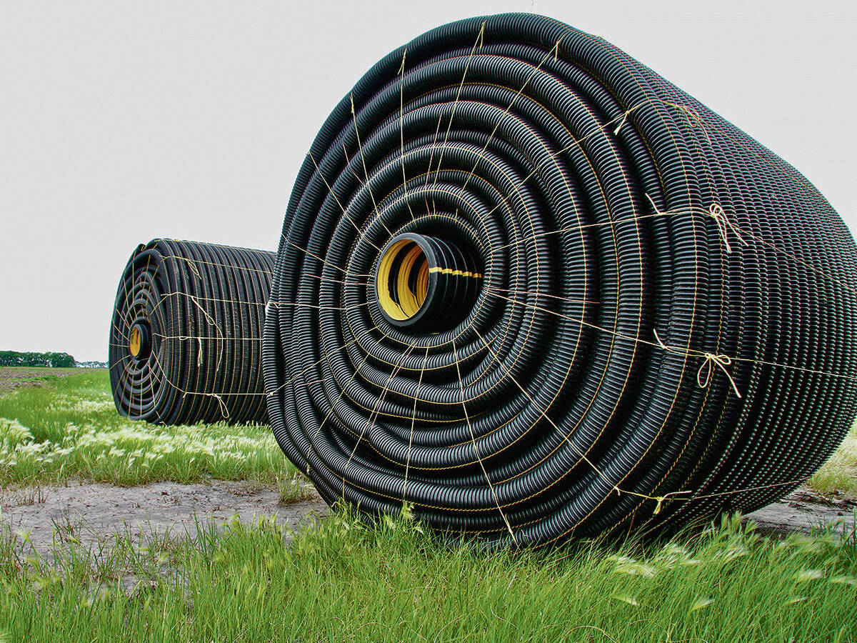 Rolls of tile drainage piping sit a field, waiting for installation.
