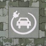 A painted symbol on a green pavement indicates a reserved parking space for electric vehicle charging. The white icon features a car with a charging cable and plug, emphasizing the transition to sustainable mobility and eco-friendly transportation in Bari, Italy, on February 10, 2025.