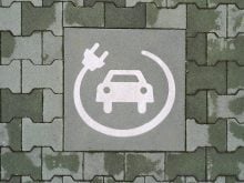 A painted symbol on a green pavement indicates a reserved parking space for electric vehicle charging. The white icon features a car with a charging cable and plug, emphasizing the transition to sustainable mobility and eco-friendly transportation in Bari, Italy, on February 10, 2025.