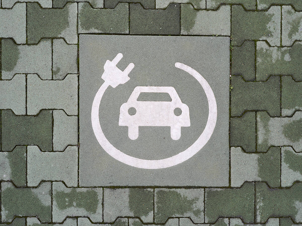 A painted symbol on a green pavement indicates a reserved parking space for electric vehicle charging. The white icon features a car with a charging cable and plug, emphasizing the transition to sustainable mobility and eco-friendly transportation in Bari, Italy, on February 10, 2025.