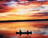 Paddlers are silhouetted against a stunning sunset at Lake Audy in Riding Mountain National Park.