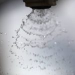 An extreme close-up of the fan-like pattern created by droplets leaving the nozzle of a sprayer.