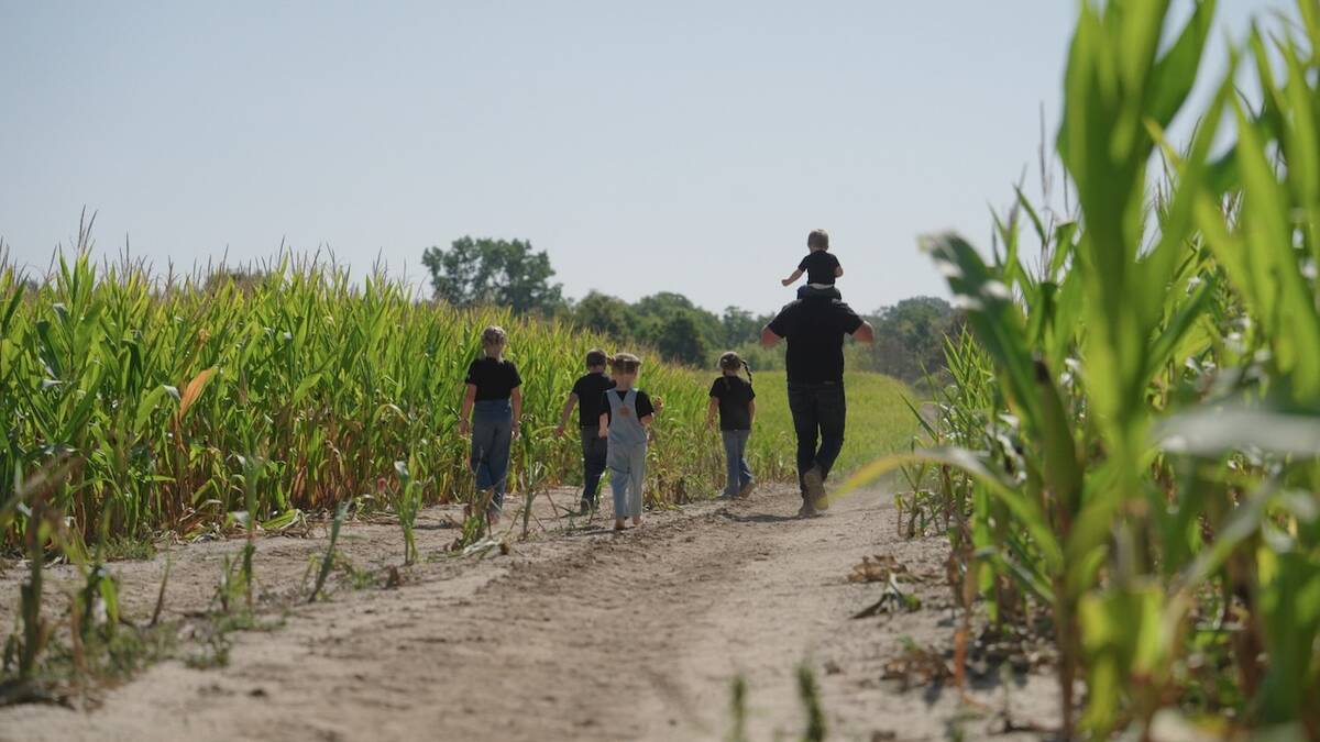Tobias Burgin and his family walk along a corn field on their farm. Photo: Courtesy of CANZA
