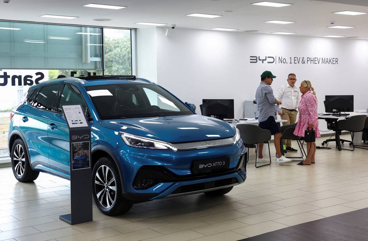 FILE PHOTO: Customers speak with a salesman at a BYD dealership in Sant Cugat del Valles, near Barcelona, Spain, September 12, 2025. REUTERS/ Albert Gea/File Photo