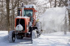 A farmer in central Manitoba blows snow out of his driveway with a tractor-mounted snowblower after a major winter storm. PHOTO: ALEXIS STOCKFORD