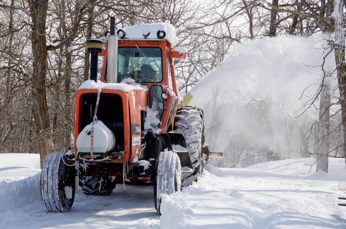 A farmer in central Manitoba blows snow out of his driveway with a tractor-mounted snowblower after a major winter storm. PHOTO: ALEXIS STOCKFORD