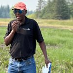 Manitoba Agriculture's Manasah Mkhabela at Arborg, Man. in July 2025, discussing trials he's conducting with University of Manitoba soil scientist Mario Tenuta to find the sweet spot for nitrification inhibitors. Photo: Don Norman