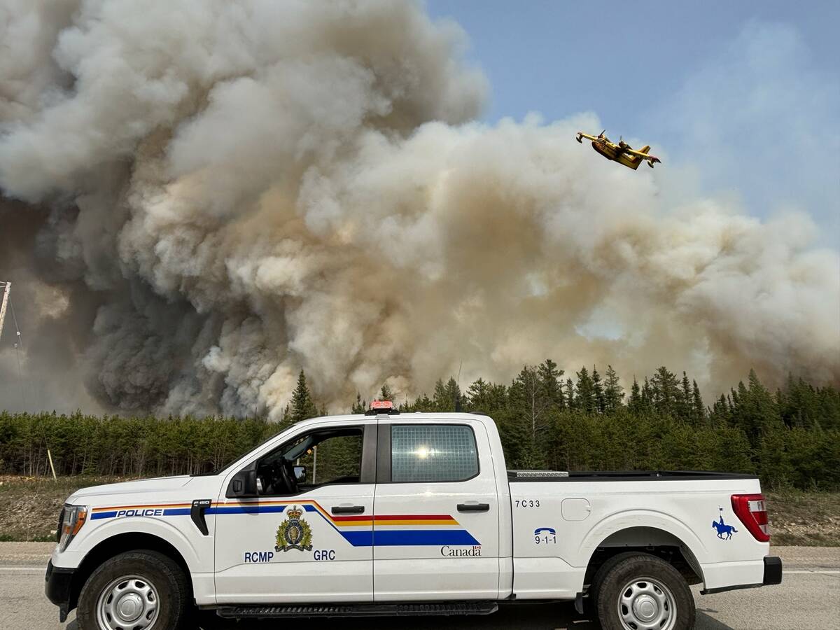 Smoke rises out of a northern Manitoba fire in late May 2025. A water bomber can be seen in the background. Photo: RCMP