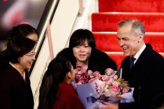 Canada’s Prime Minister Mark Carney receives flowers from Lu You Ci, 11, upon his arrival at Beijing Capital International Airport, during the first visit by a Canadian Prime Minister to China since 2017, in Beijing, China January 14, 2026.  Photo: REUTERS/Carlos Osorio
