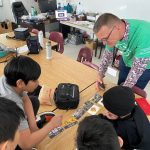 Agriculture volunteer explains a concept to students seated at a table during a classroom visit. Photo: Agriculture in the Classroom - Manitoba