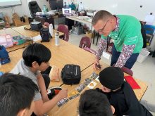 Agriculture volunteer explains a concept to students seated at a table during a classroom visit. Photo: Agriculture in the Classroom - Manitoba