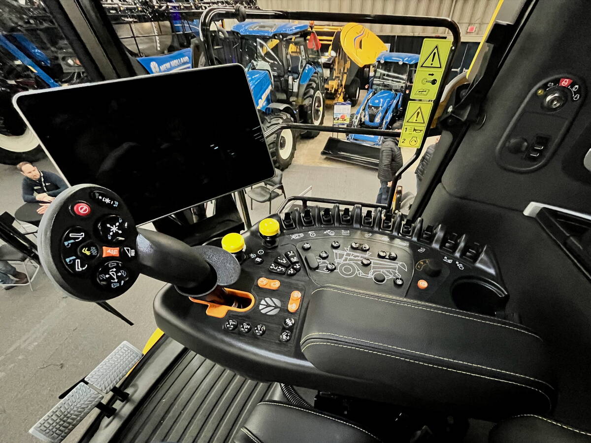 View from inside a modern agricultural equipment cab showing multiple digital display screens, a control joystick, and a steering wheel. Photo: Alexis Stockford