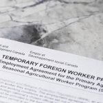 Close-up of a Canada Temporary Foreign Worker Program application form for the Seasonal Agricultural Worker Program, reflecting recent federal changes to rural worker caps. Photo: Getty Images Plus.