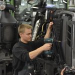 A worker uses a cordless drill to assemble a tractor on a factory production line. Photo: AGCO/Fendt.