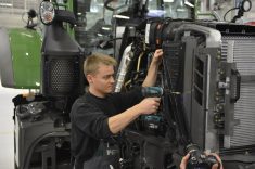 A worker uses a cordless drill to assemble a tractor on a factory production line. Photo: AGCO/Fendt.