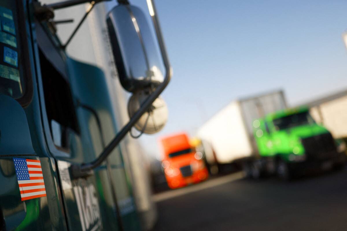 Transport trucks lined up at what appears to be a U.S.-Mexico border crossing, with an American flag visible on the side mirror of the nearest truck. Mexico and the U.S. began bilateral CUSMA discussions in March ahead of the formal joint review scheduled for later this year. Photo: Jose Luis Gonzalez/Reuters