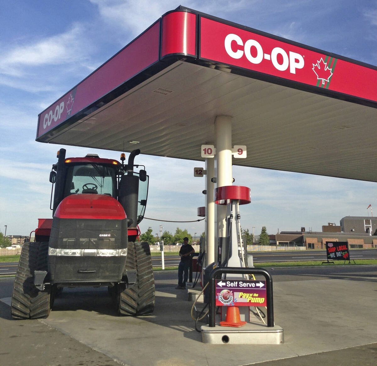 A red tractor fuels up at a Co-op gas station, illustrating rising diesel costs hitting Prairie farm operations. Photo: file