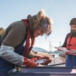 Two salmon farmers inspect a fish. Salmon is in high demand for Canadian aquaculture. Photo: Supplied
