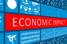 A digital display screen showing the words "Economic Impact" in white text on a red banner, surrounded by blue panels displaying financial charts, graphs and world maps. Photo: Getty Images