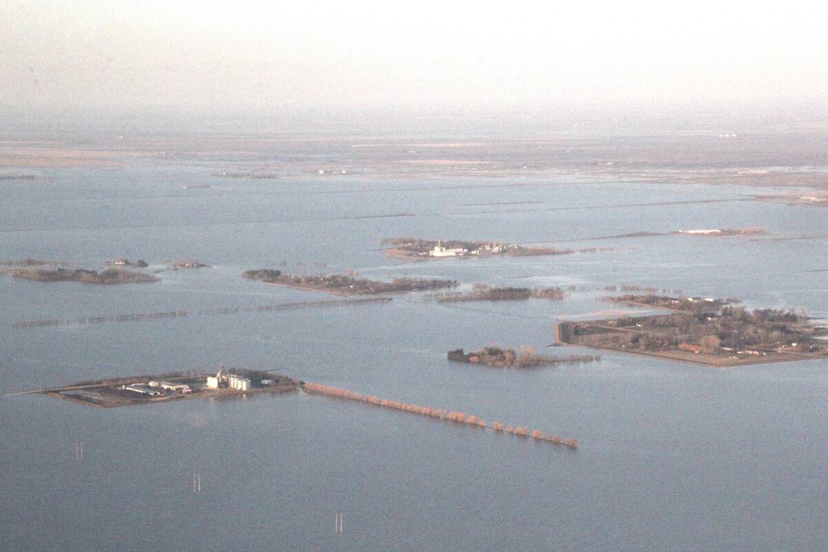 Aerial view of widespread flooding near Rosenort in May 2022, shows farm buildings, a grain elevator and communities surrounded by floodwater stretching to the horizon. Photo: Allan Dawson