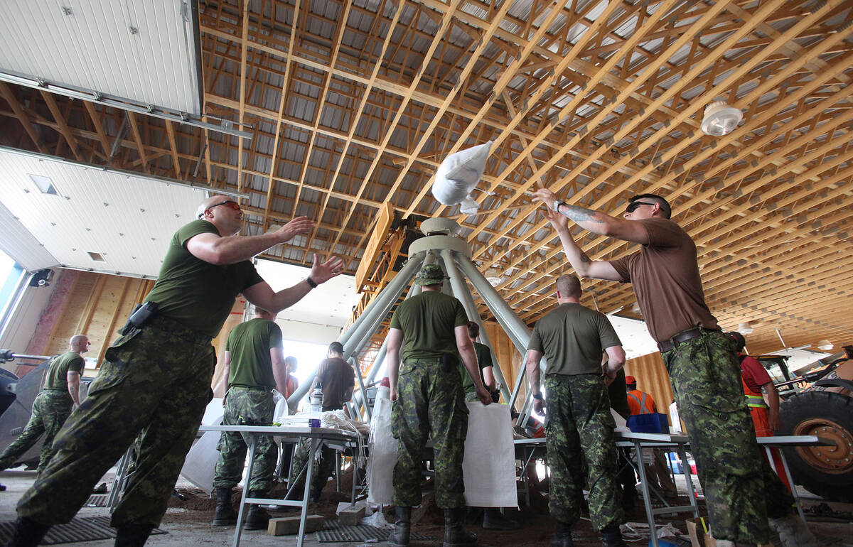 Canadian Armed Forces members tossing sandbags inside a large building during flood response operations in Portage la Prairie, Man., in 2014. Photo: file